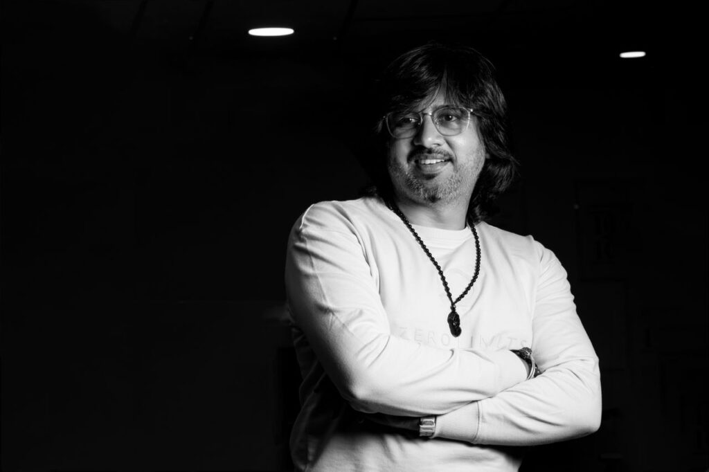 Striking black and white portrait of a confident man in casual attire with folded arms.